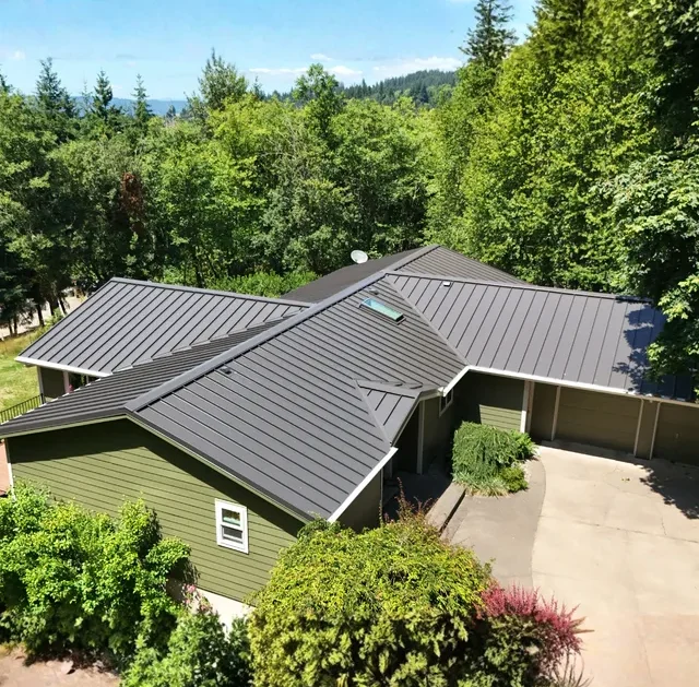 Aerial view of home with dark standing seam metal roof surrounded by trees in Vancouver, WA