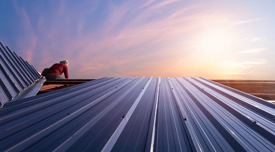 Roofer installing metal roofing panels at sunset in Vancouver, WA